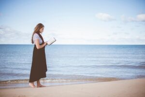 Woman reading book near sea